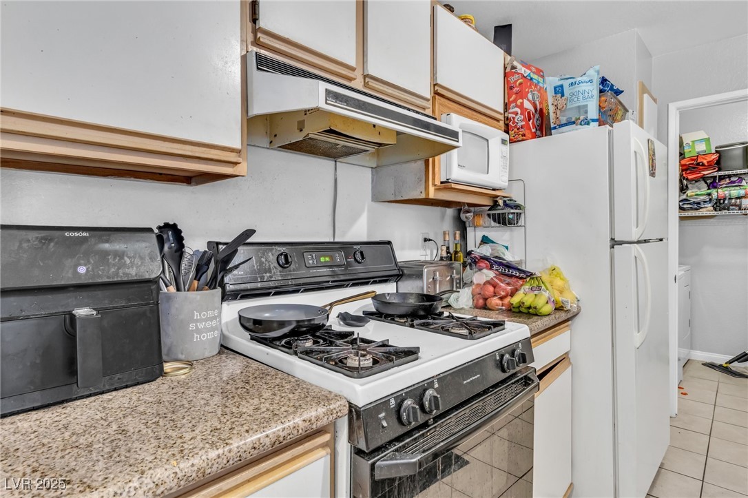 2200 South Fort Apache Road, Unit 1007 Las Vegas, NV 89117 - Photo 11 of 30 Kitchen featuring light tile patterned floors, white appliances, white cabinetry, and under cabinet range hood
