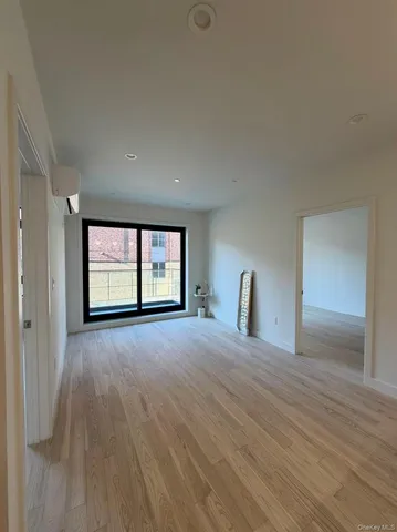 a view of an empty room with a window and wooden floor