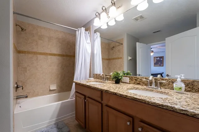 a bathroom with a granite countertop sink a large mirror and a bathtub with shower