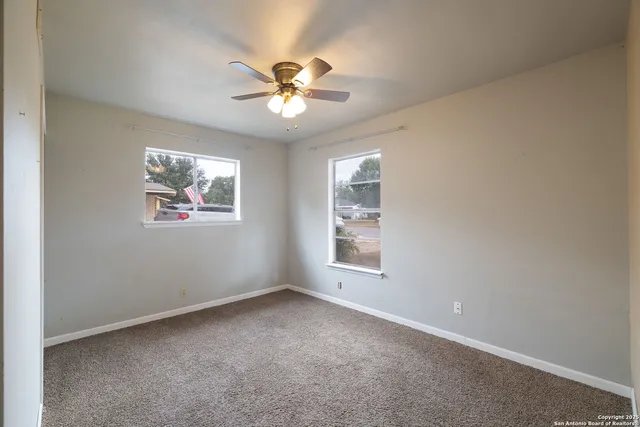 an empty room with windows and fan