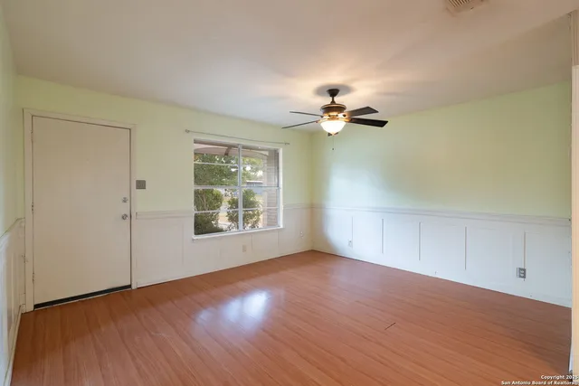 a view of an empty room with a window and wooden floor