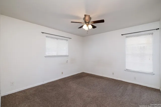 an empty room with a window and a fan