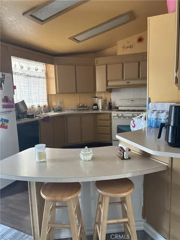 a kitchen with stainless steel appliances a table chairs sink and cabinets