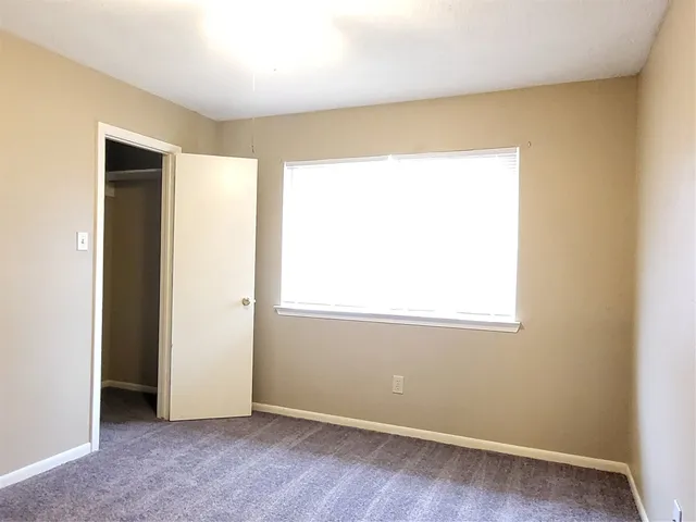an empty room with windows and chandelier fan
