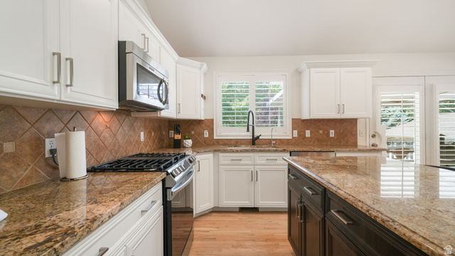 11128 South Barrett Pk Circle Sandy, UT 84092 - Photo 8 of 36 Kitchen featuring white cabinetry, granite countertops, a diamond-patterned tile backsplash, stainless steel appliances, and a central island with contrasting dark cabinetry