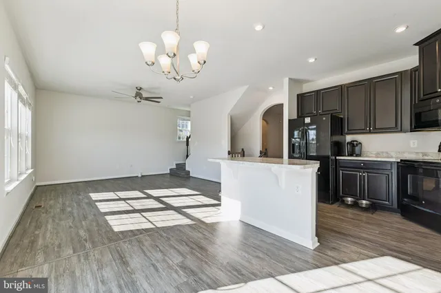 a kitchen with kitchen island granite countertop a stove top oven a sink cabinets and wooden floor