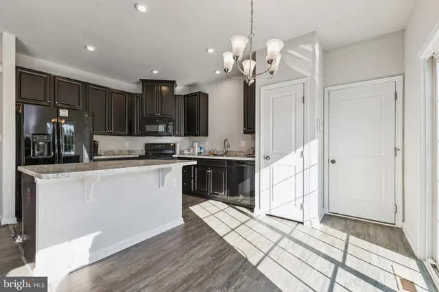 a kitchen with stainless steel appliances granite countertop a refrigerator a sink dishwasher a stove and white cabinets with wooden floor