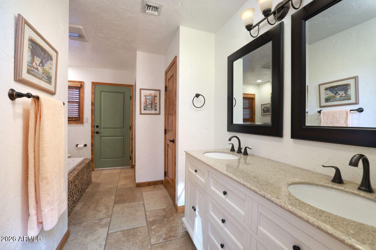 8741 East Woodland Road Tucson, AZ 85749 - Photo 28 of 51 a bathroom with a granite countertop sink mirror and a