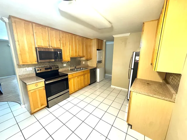 a kitchen with stainless steel appliances a stove top oven a sink a counter top space and cabinets