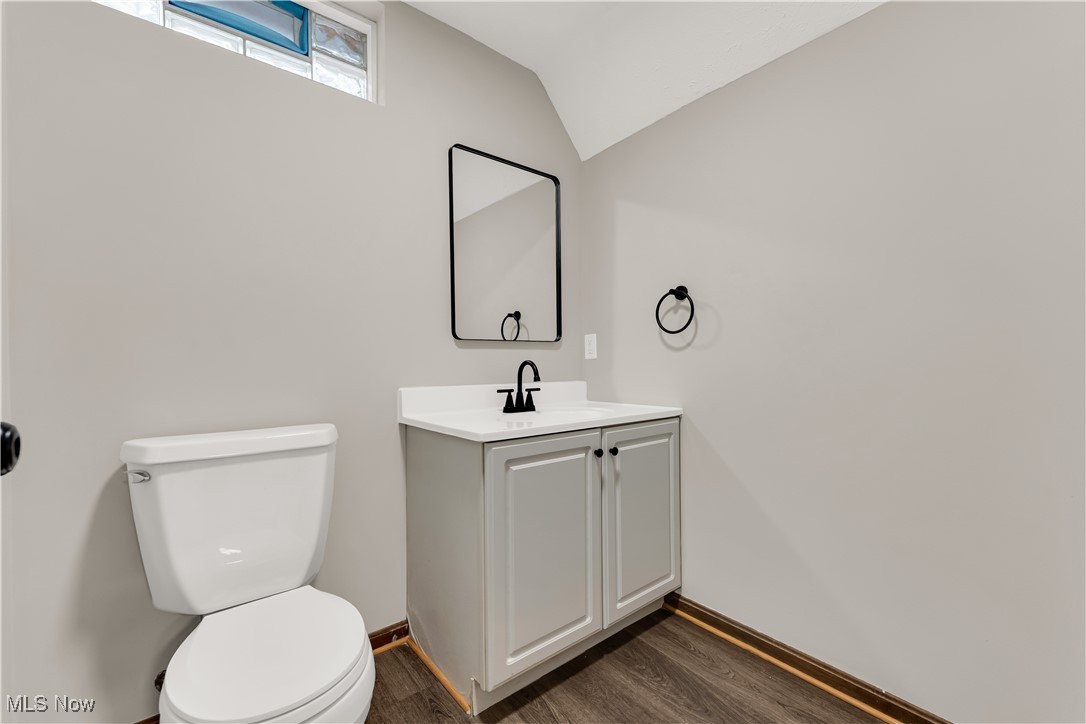 5327 Jaycox Road North Ridgeville, OH 44039 - Photo 28 of 36 Bathroom featuring wood finished floors, toilet, vanity, vaulted ceiling, and baseboards