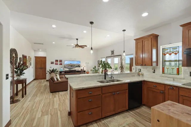a spacious kitchen with stainless steel appliances granite countertop a sink dishwasher and wooden cabinets with wooden floor