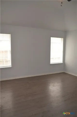 an empty room with a ceiling fan and window