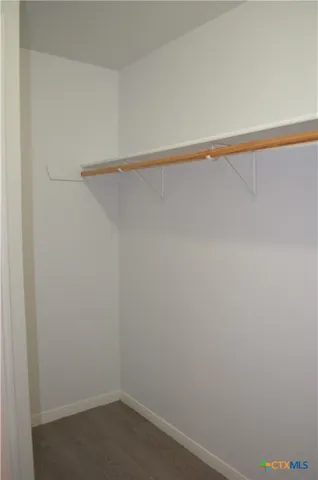 an empty room with a chandelier fan and windows