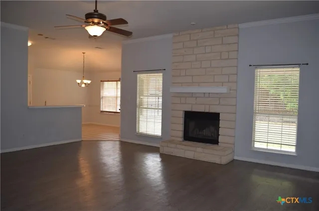 an empty room with windows fireplace and wooden floor