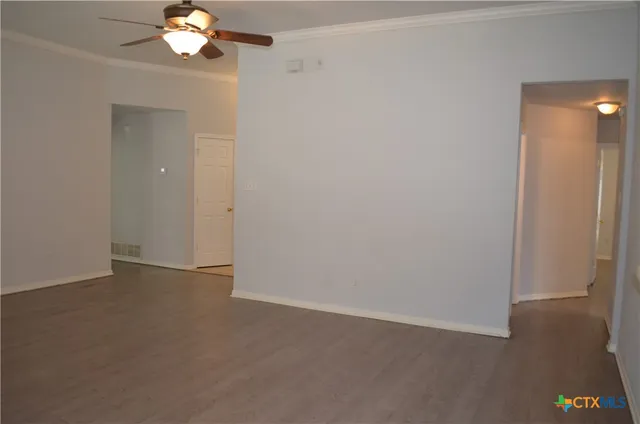 an empty room with a chandelier fan and windows
