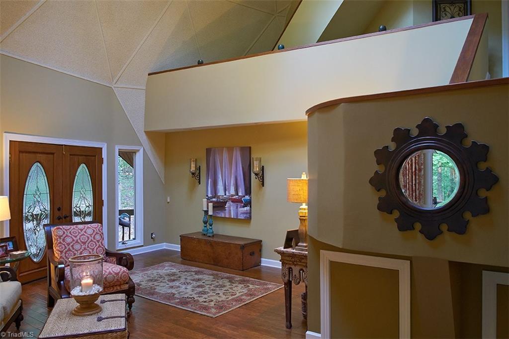 5205 Rambling Road Greensboro, NC 27409 - Photo 2 of 30 Beautiful leaded glass doors open to great room with 30 foot ceilings! Second level loft area leads into master bedroom & master bath. Stairs then continue to 3rd floor bonus room! Note the 2 hidden storage areas on the right below the stairs!