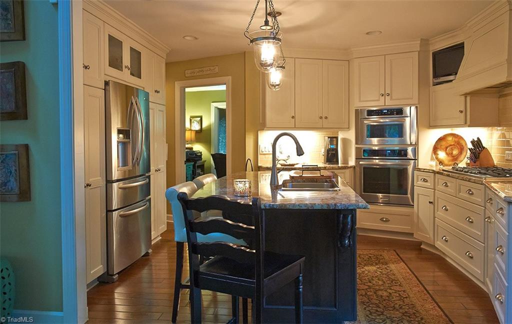 5205 Rambling Road Greensboro, NC 27409 - Photo 13 of 30 Another view of the totally updated kitchen with custom cabinets, stainless steel appliances, granite, subway tile, and a beautiful island! Door from hallway leads into 3rd bedroom which is currently being used as an office.