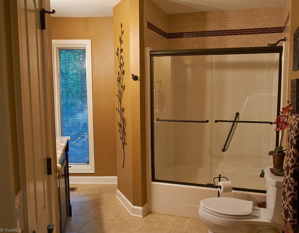 5205 Rambling Road Greensboro, NC 27409 - Photo 16 of 30 Main level bathroom updated with custom vanity, granite counter top, tile floors, and tile above the shower.