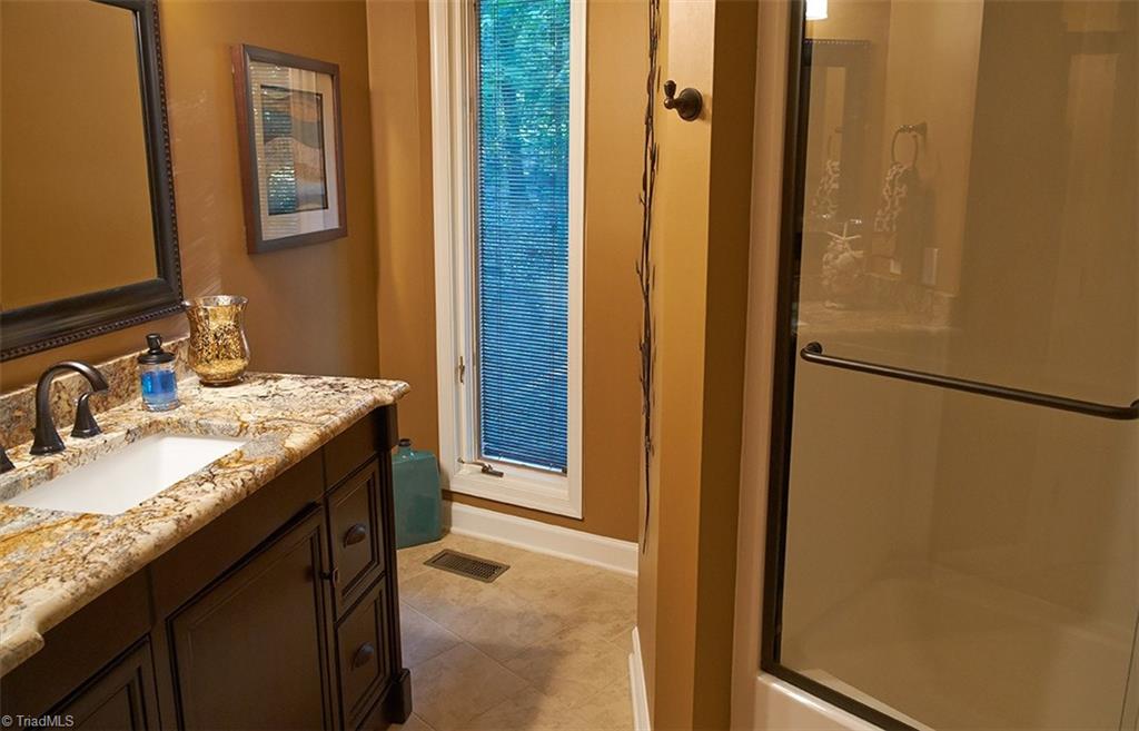 5205 Rambling Road Greensboro, NC 27409 - Photo 17 of 30 Main level bathroom. Beautiful updated vanity, granite counter top, and tile floors!