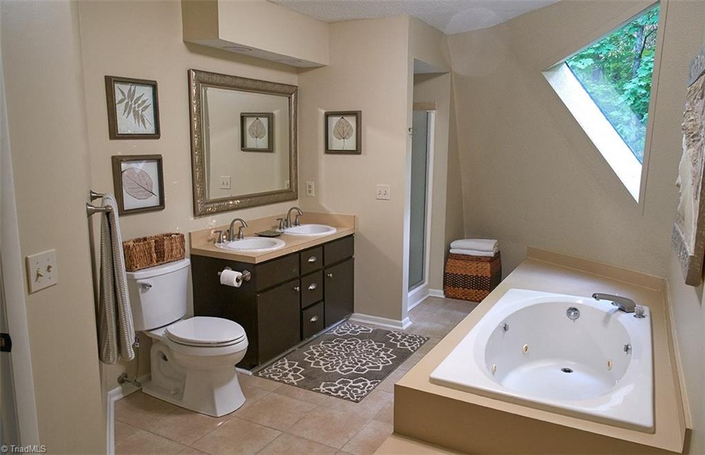 5205 Rambling Road Greensboro, NC 27409 - Photo 22 of 30 Spacious master bathroom with tile floors, jetted tub, separate shower, double vanity, & a unique triangle shaped window!