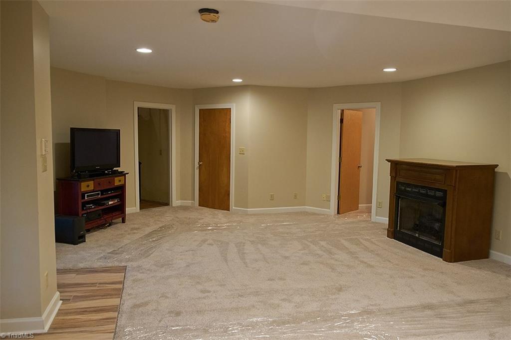 5205 Rambling Road Greensboro, NC 27409 - Photo 26 of 30 Finished basement with recessed lighting and new carpet. Closed door leads to a full bathroom, and open door on the right leads to a room that's currently being used as a bedroom. Vent-less gas log fireplace for cold nights!