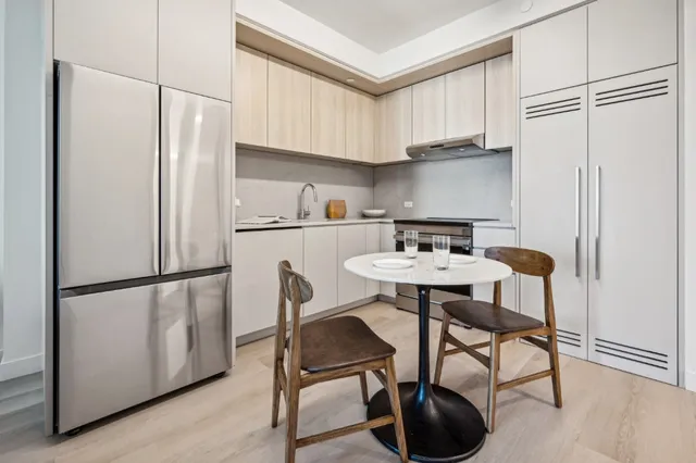 a kitchen with stainless steel appliances a refrigerator a table and chairs