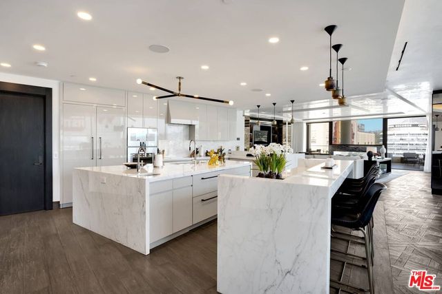 a large white kitchen with lots of counter space and stainless steel appliances