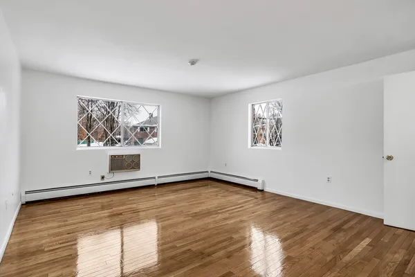 a view of an empty room with window and wooden floor