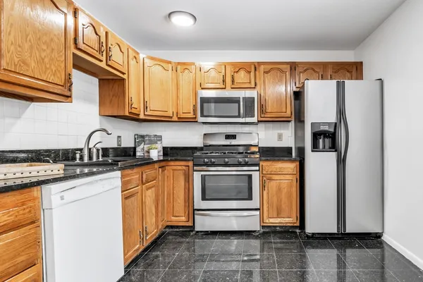 a kitchen with stainless steel appliances granite countertop a refrigerator stove top oven a sink and dishwasher