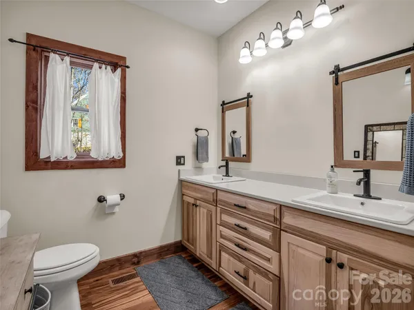 a bathroom with a toilet a sink a mirror and a window