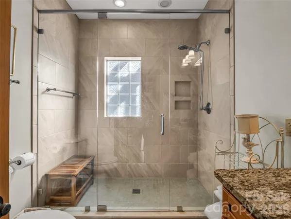 a bathroom with a granite countertop shower a mirror and a sink