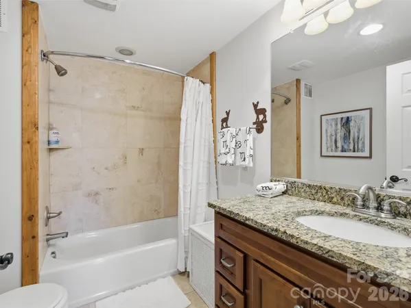 a bathroom with a granite countertop sink a mirror a bathtub and shower
