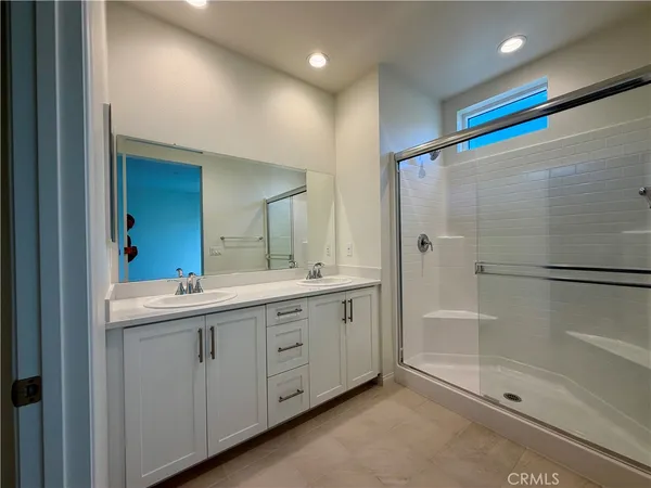 a bathroom with a double vanity sink mirror and shower