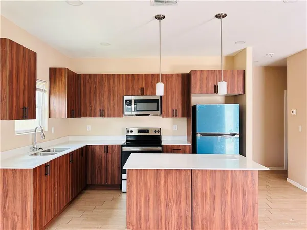 a kitchen with stainless steel appliances a sink a refrigerator a center island a stove and a center island
