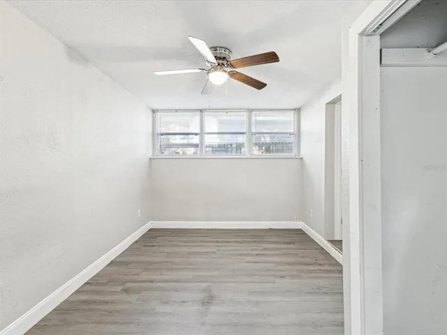 a view of a room with wooden floor and ceiling fan