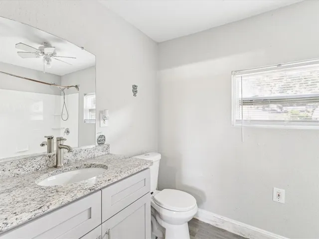 a bathroom with a granite countertop sink a toilet and a mirror