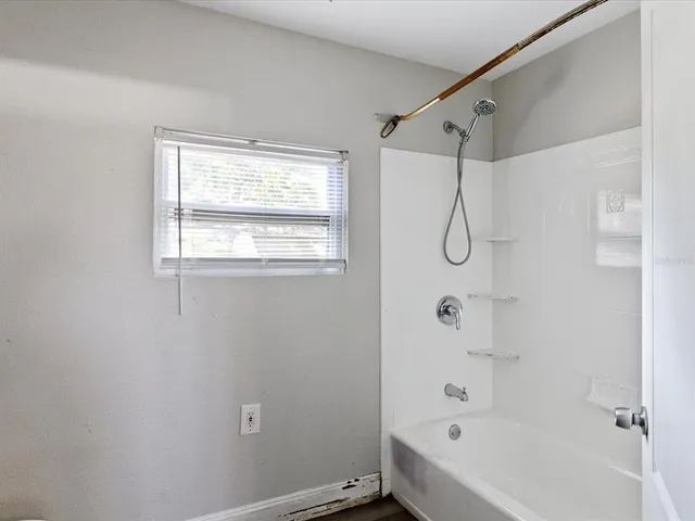 a bathroom with a bathtub a shower and a window