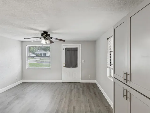 a view of empty room with wooden floor and fan