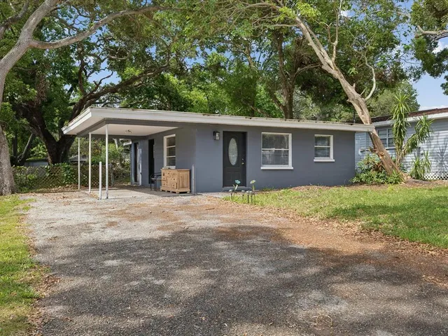 a view of a house with a yard and large trees