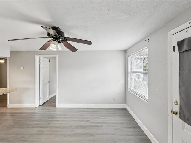 a view of an empty room with wooden floor and a window