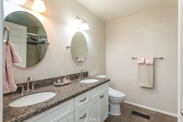 a bathroom with a granite countertop toilet a sink and a mirror
