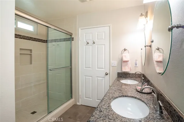 a bathroom with a granite countertop sink a mirror and shower