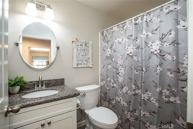 a bathroom with a granite countertop sink mirror vanity and toilet