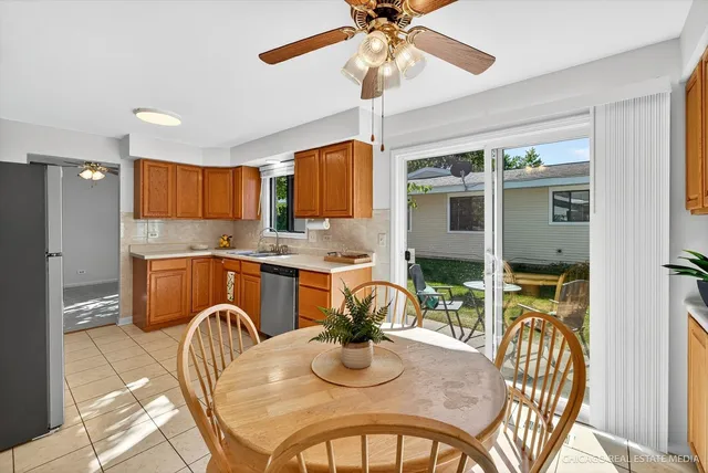 a kitchen with stainless steel appliances granite countertop a stove a refrigerator a kitchen island a dining table and chairs with wooden floor