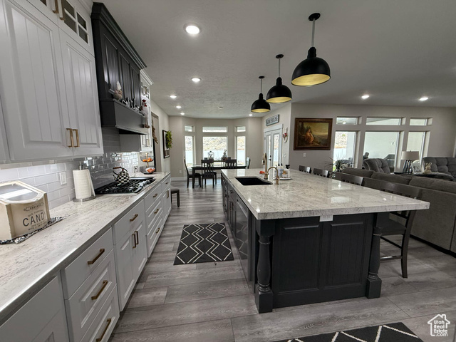 1240 West 2360 North Helper, UT 84526 - Photo 22 of 79 Kitchen with an island with sink, backsplash, a sink, wood finished floors, and stainless steel gas stovetop