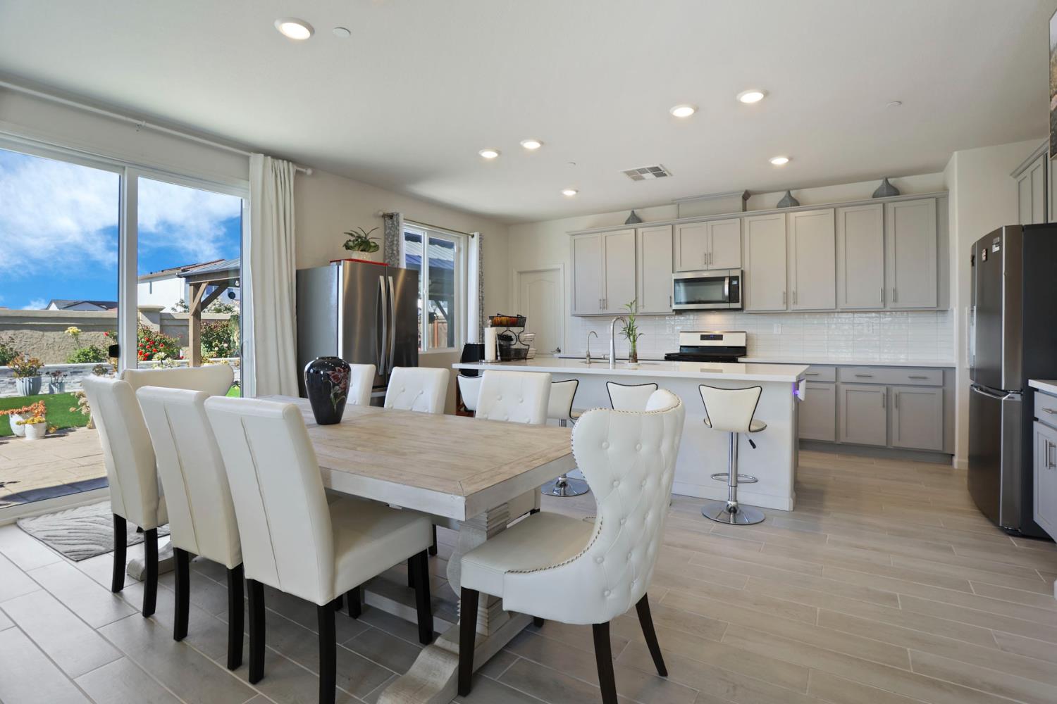 6949 Foraker Drive Stockton, CA 95219 - Photo 10 of 34 a kitchen with stainless steel appliances granite countertop a dining table chairs refrigerator and cabinets
