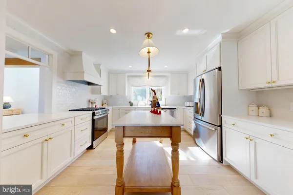 a kitchen with kitchen island stainless steel appliances a stove refrigerator sink and cabinets