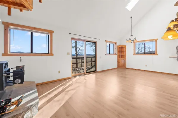 a view of an empty room with window and wooden floor