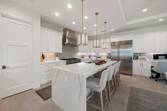 a kitchen with stainless steel appliances kitchen island granite countertop a sink a stove and a refrigerator