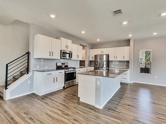 10403 Bramble Berry Drive Austin, TX 78748 - Photo 2 of 21 a large kitchen with stainless steel appliances granite countertop a large center island a stove a sink a refrigerator and white cabinets with wooden floor